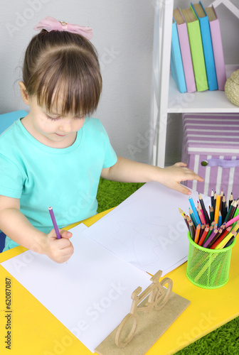 Little girl draws sitting a...