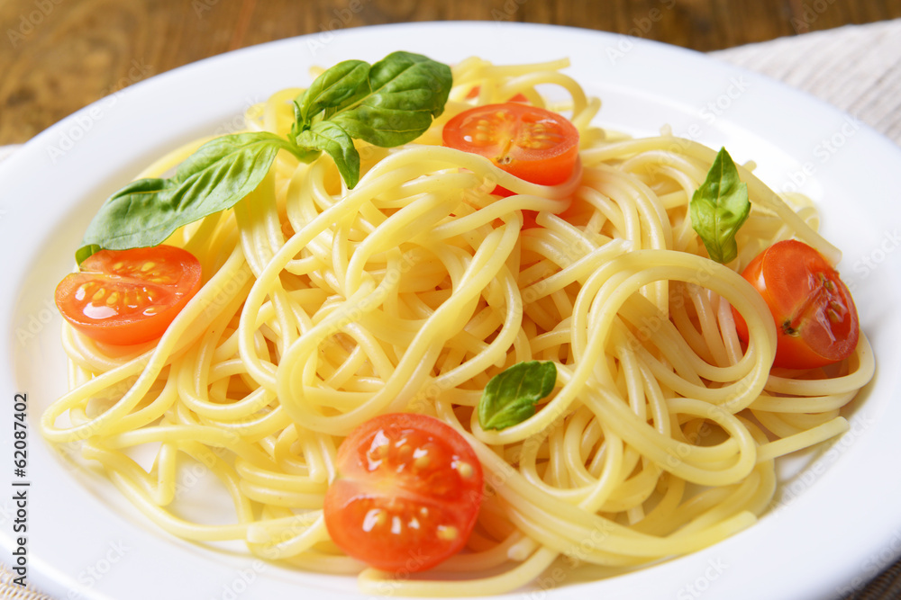 Delicious spaghetti with tomatoes on plate on table close-up Delicious spaghetti with tomatoes on plate on table close-up