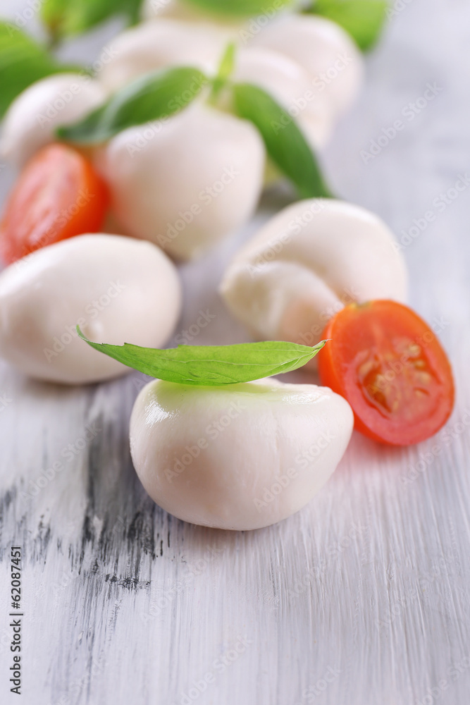 Tasty mozzarella cheese with basil and tomatoes, on wooden Tasty mozzarella cheese with basil and tomatoes, on wooden