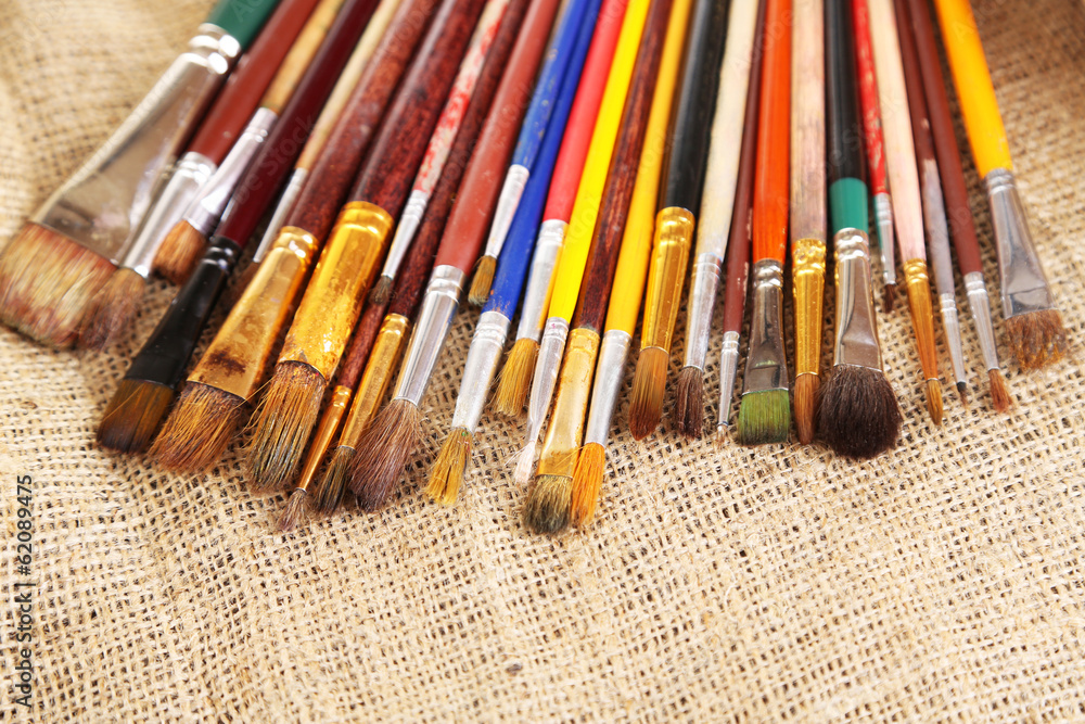 Fototapeta premium Many brushes in paints on sackcloth background