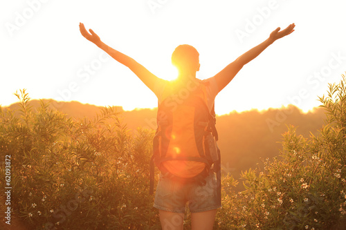 cheering woman hiker open arms at sunrise mountain peak