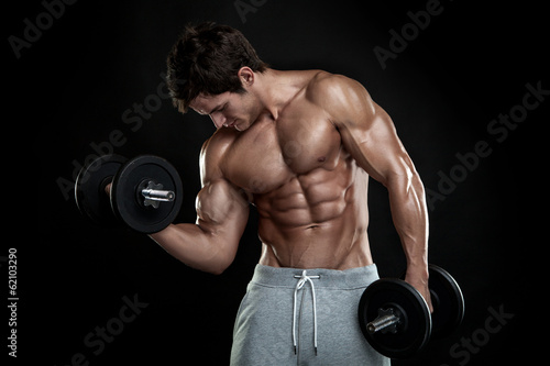 Muscular bodybuilder guy doing exercises with dumbbells over bla