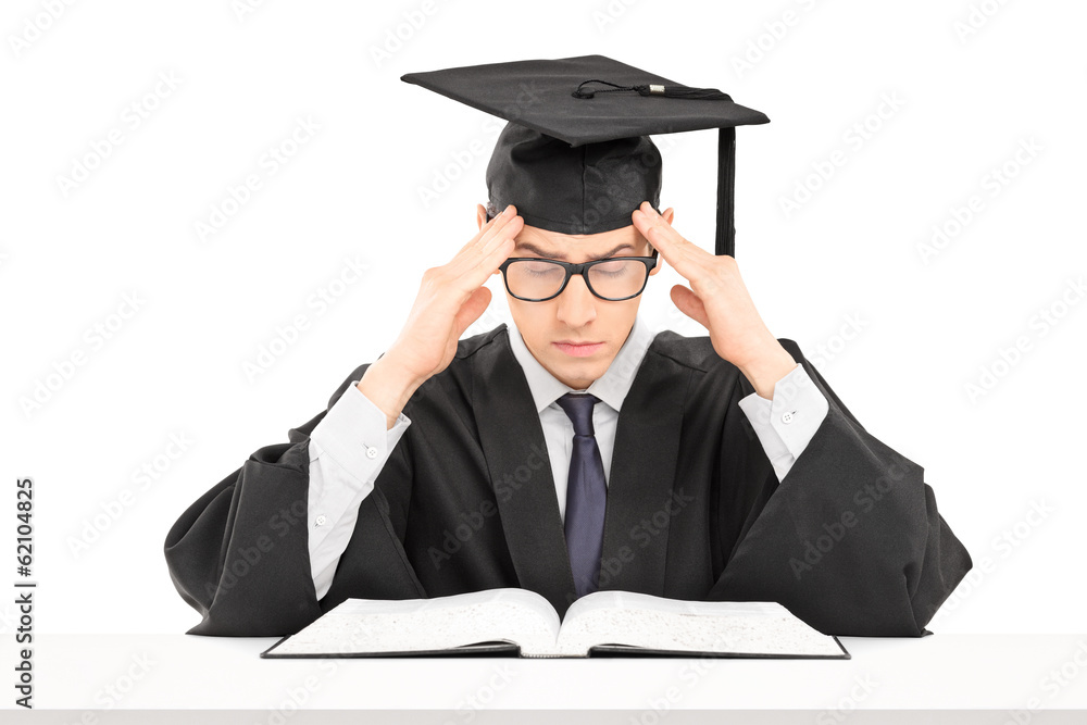 Student in graduation gown trying to concentrate on studying Student in graduation gown trying to concentrate on studying