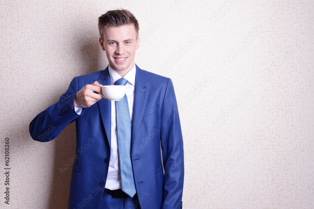 Portrait of businessman with cup of coffee near wall Portrait of businessman with cup of coffee near wall