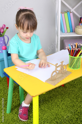 Little girl draws sitting a...
