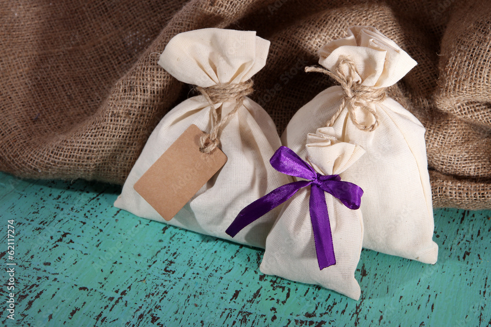 Sacks on color wooden table, on sackcloth background Sacks on color wooden table, on sackcloth background