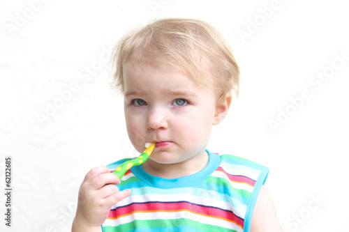Portrait of toddler girl wearing colorful bib eating porridge