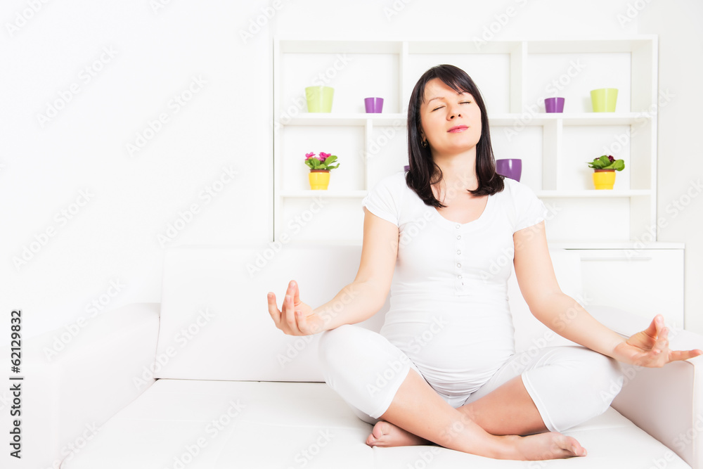 Beautiful, pregnant woman sitting in a lotus position while meditating.Copy space Beautiful, pregnant woman sitting in a lotus position while meditating.Copy space