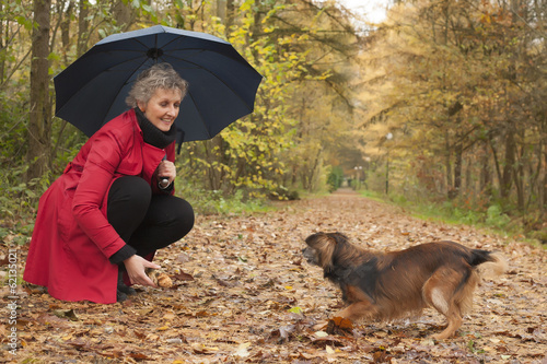 Woman with umbrella playing with her dog photo