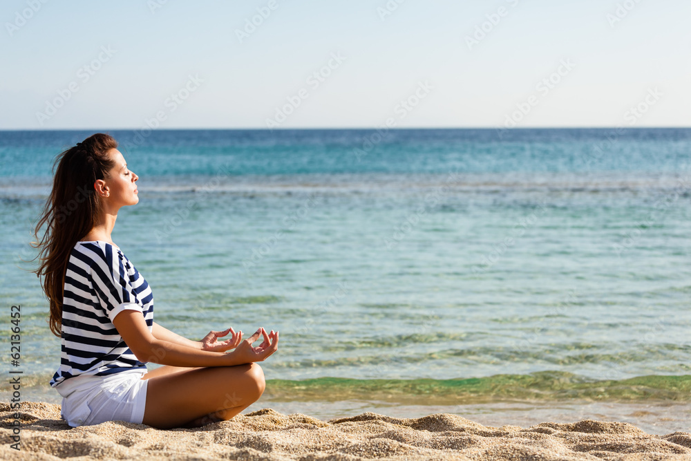 Beautiful woman meditating at the beach.Copy space
