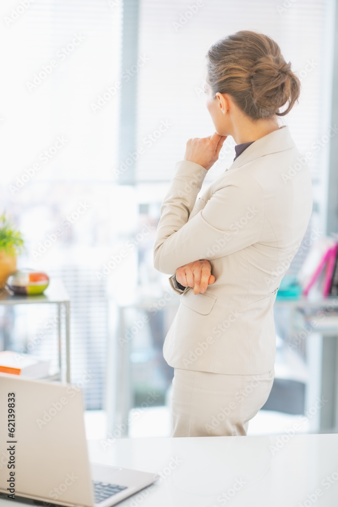 Thoughtful business woman standing in office. rear view Thoughtful business woman standing in office. rear view