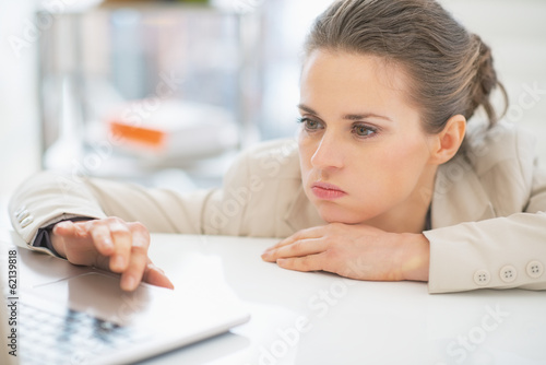 Frustrated business woman working with laptop in office photo