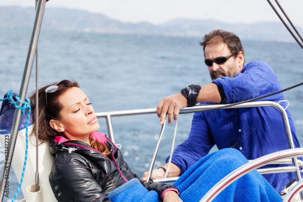 Beautiful lady enjoying on a sailboat, mature man looking at her.