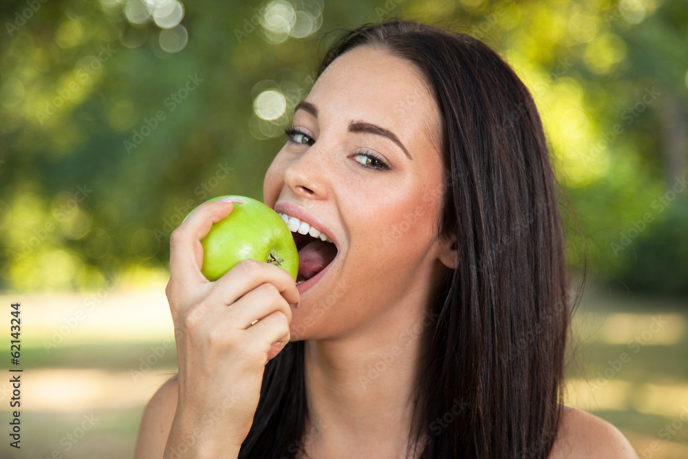 Beautiful young woman with toothy smile biting green fresh apple Beautiful young woman with toothy smile biting green fresh apple