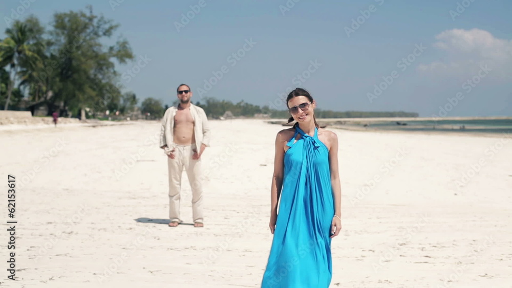 Happy woman standing on beautiful beach, man in background Happy woman standing on beautiful beach, man in background