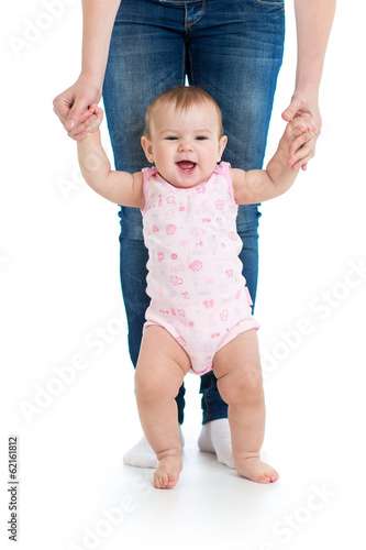 little baby girl doing first steps with help of mom