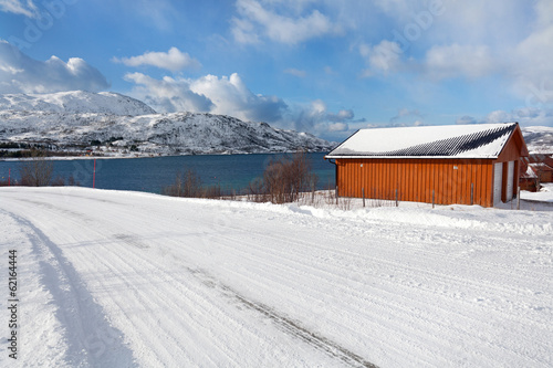 Isolated house next to a snowy fjord
