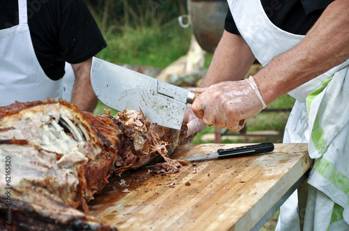 Cuisinier découpant de la viande d'agneau entier, barbecue ou méchoui en été