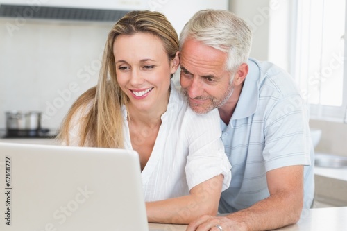 Happy couple using laptop together at the counter