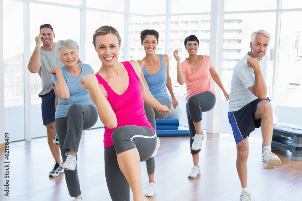 Smiling people doing power fitness exercise at yoga class