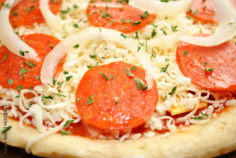 Close-Up of a Raw Pepperoni Pizza with Onions Close-Up of a Raw Pepperoni Pizza with Onions