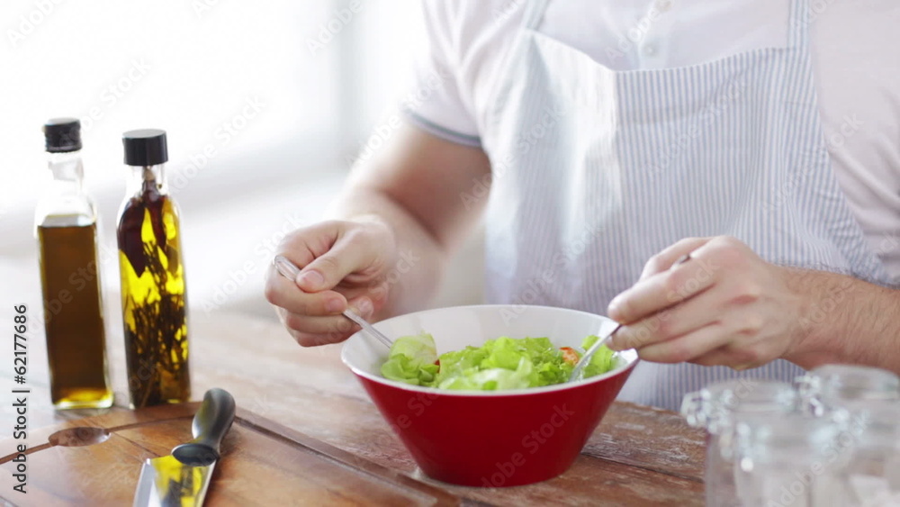 close of male hands mixing salad in a bowl close of male hands mixing salad in a bowl