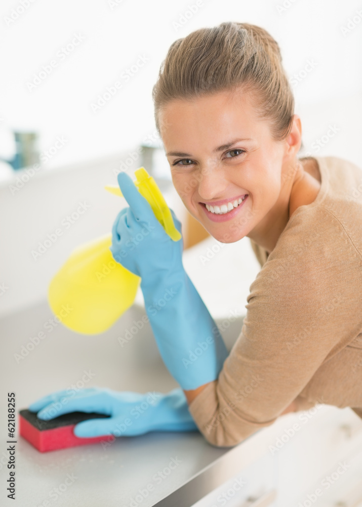 Portrait of happy housewife with spray bottle and sponge in bath Portrait of happy housewife with spray bottle and sponge in bath