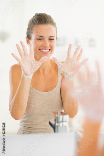 Portrait of happy young woman showing hands with soap foam