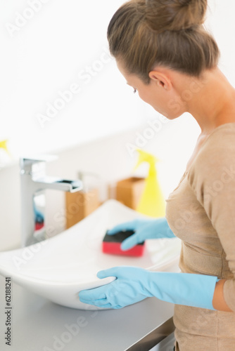 Closeup on housewife cleaning sink with sponge