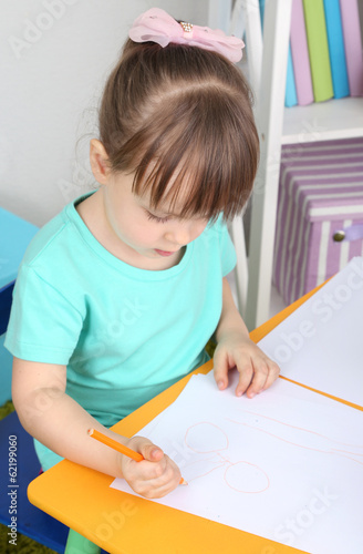 Little girl draws sitting a...