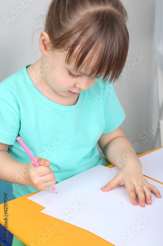 Little girl draws sitting a...