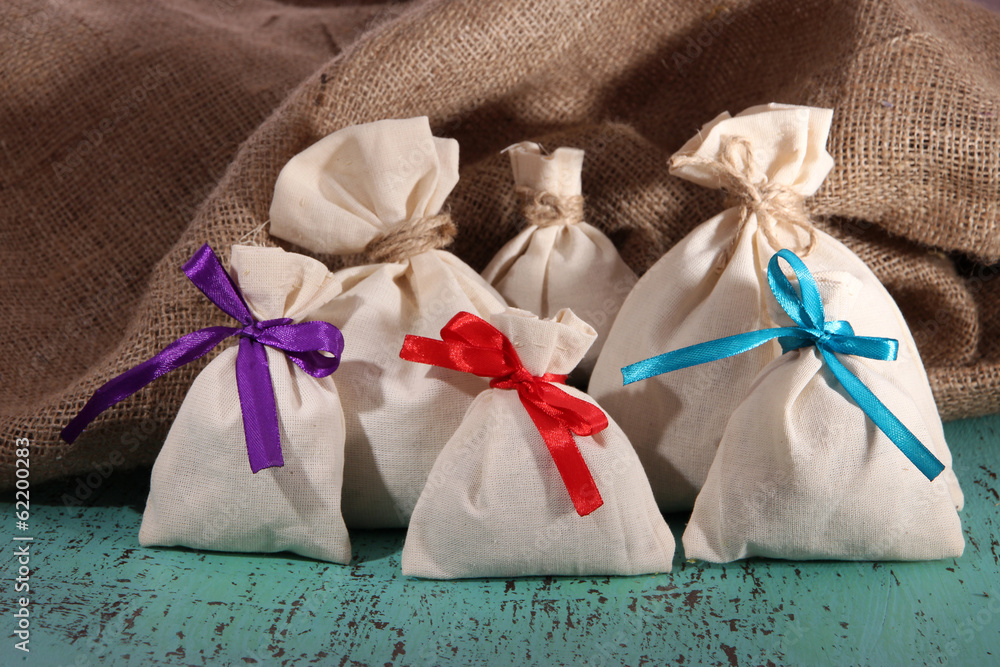 Sacks on color wooden table, on sackcloth background Sacks on color wooden table, on sackcloth background