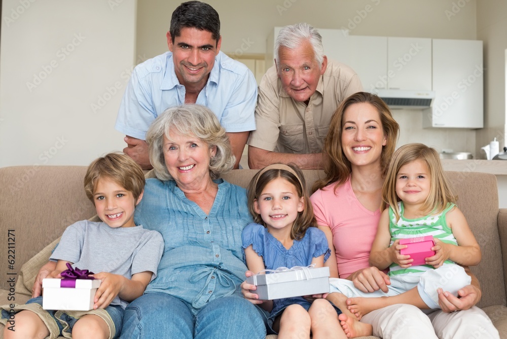 Siblings holding gifts with family in living room