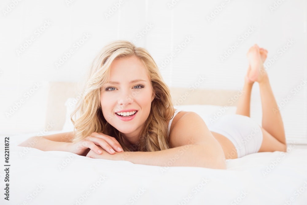 Fototapeta premium Pretty young blonde smiling at camera on bed