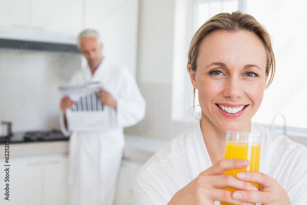 Happy woman drinking orange juice in bathrobe Happy woman drinking orange juice in bathrobe