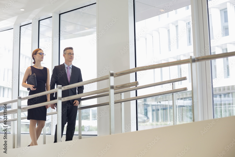 Business people walking by railing in office Business people walking by railing in office