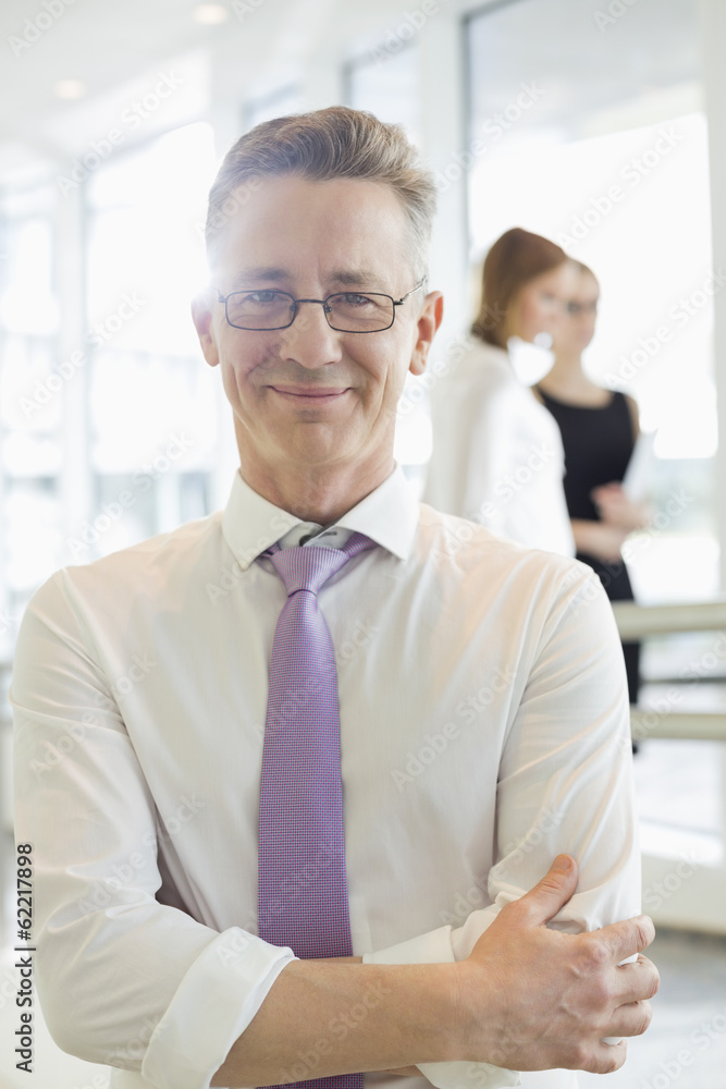 Portrait of confident businessman standing arms crossed in office Portrait of confident businessman standing arms crossed in office