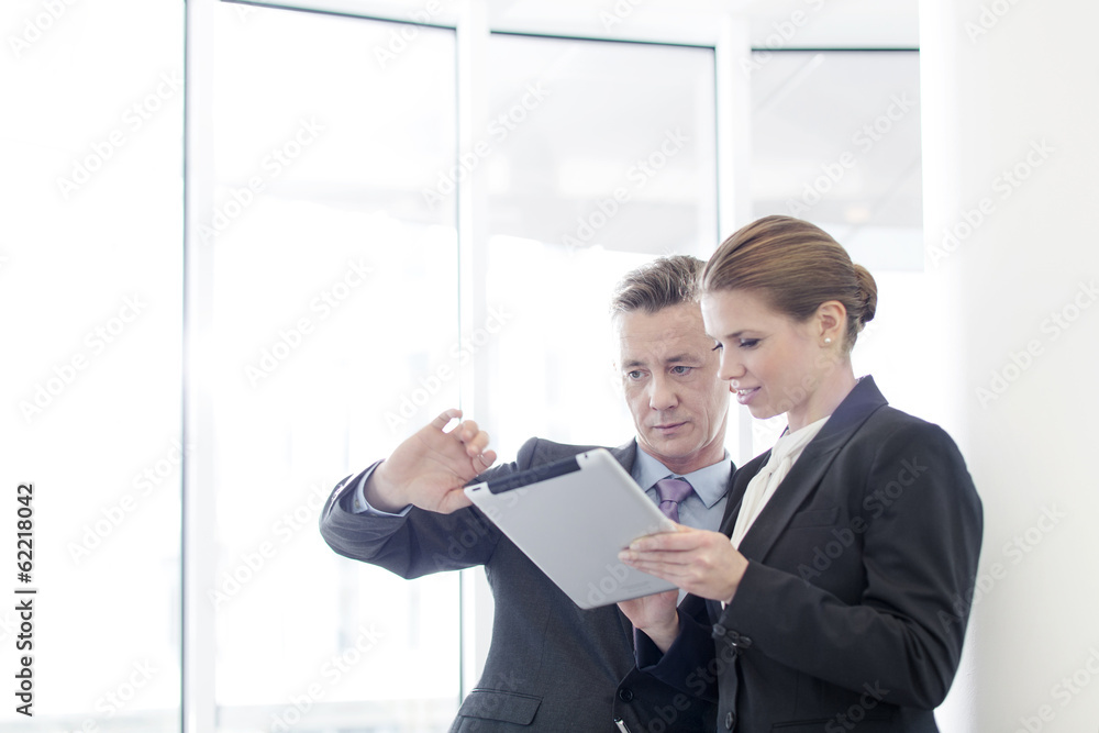 Businessman using tablet PC with female colleague in office Businessman using tablet PC with female colleague in office