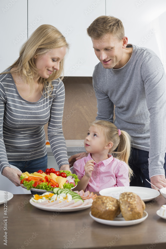 Happy parents with daughter having meal in kitchen Happy parents with daughter having meal in kitchen
