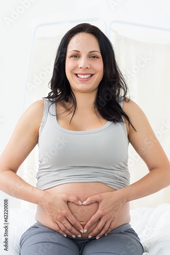 Happy pregnant woman making heart shape on belly Free Download Happy pregnant woman making heart shape on belly - GFXLoad