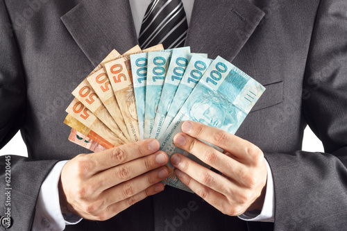 A businessman in a suit showing brazilian money