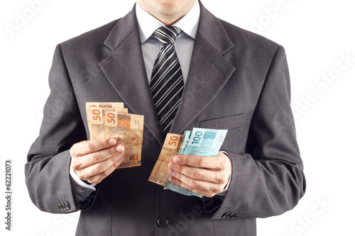 A businessman in a suit counting brazilian money