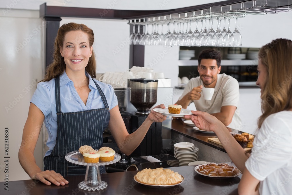 Female cafe owner with sweet snacks and couple at counter in Female cafe owner with sweet snacks and couple at counter in