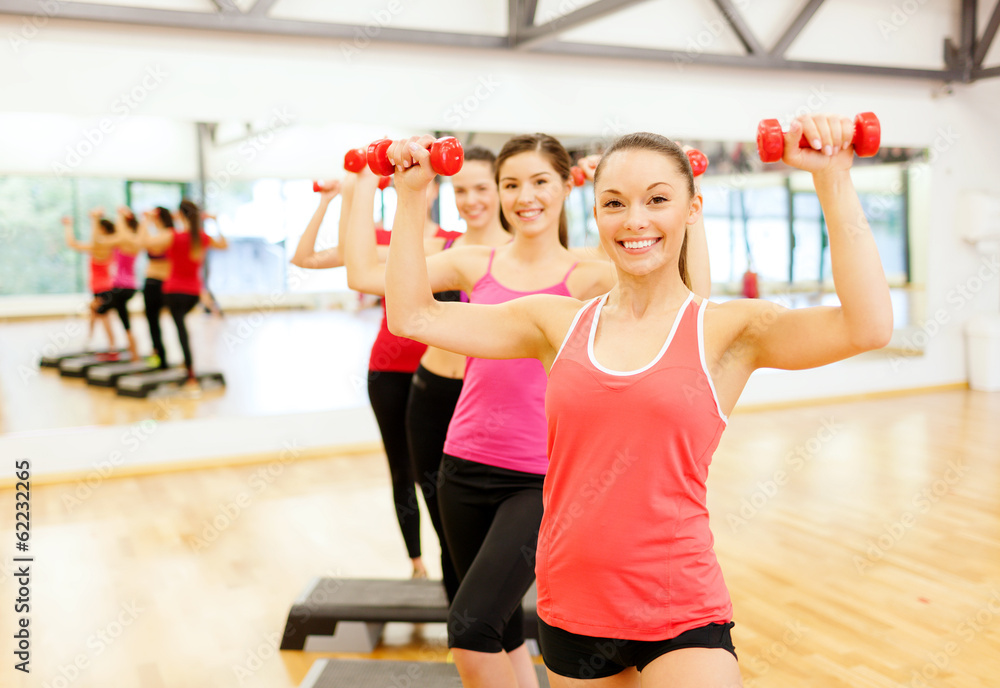 group of smiling female with dumbbells and step group of smiling female with dumbbells and step