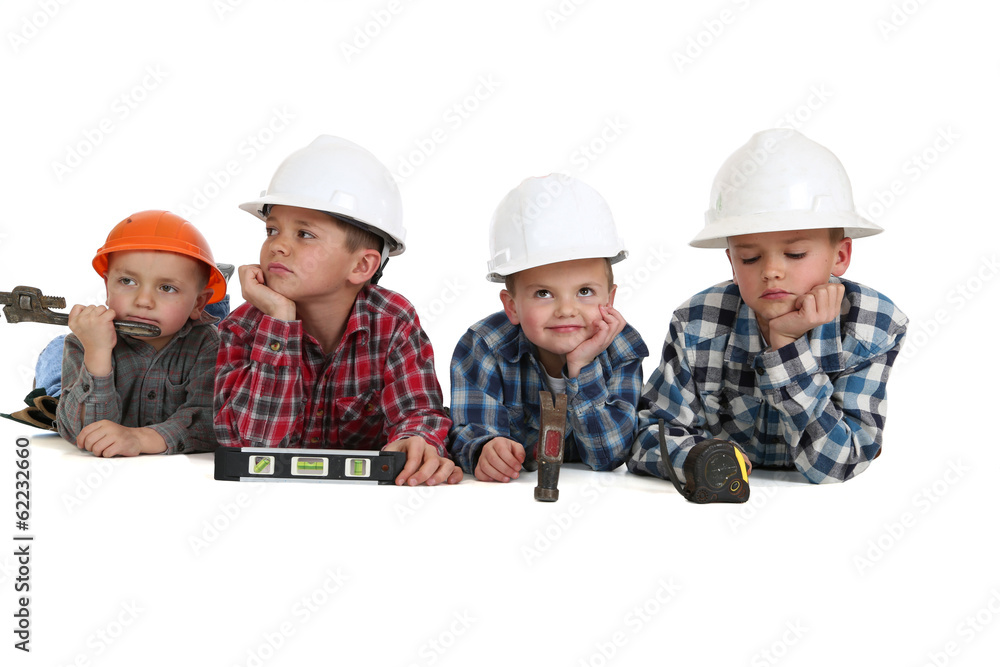Boys laying down with tools wearing construction hardhats Boys laying down with tools wearing construction hardhats