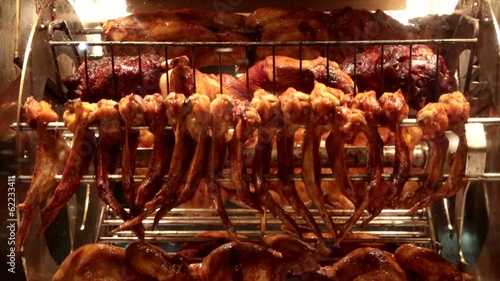Куриные тушки и крылья жарятся на вращающемся гриле