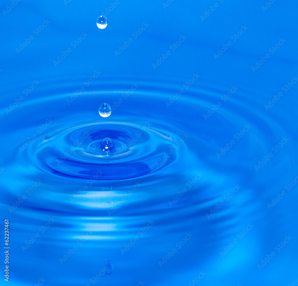 a drop of water falling in blue water. macro a drop of water falling in blue water. macro