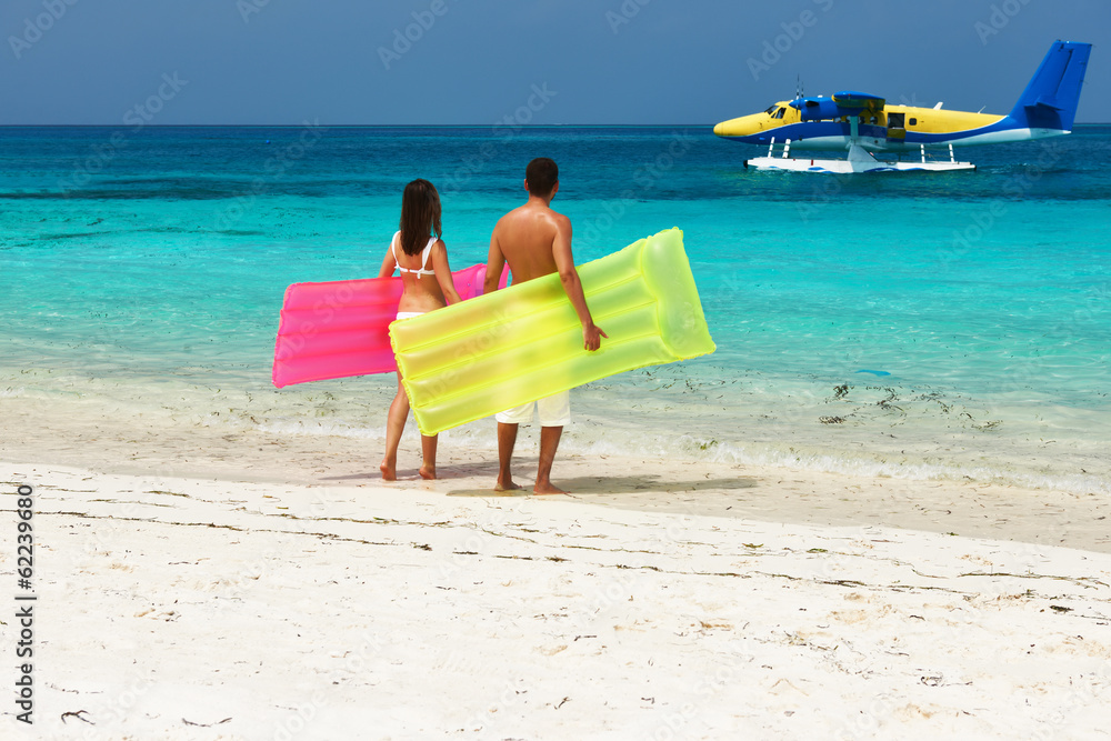 Couple with inflatable rafts looking at seaplane on beach Couple with inflatable rafts looking at seaplane on beach