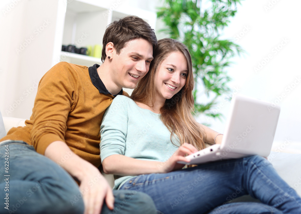 Portrait of a smiling young couple using laptop at home indoor Portrait of a smiling young couple using laptop at home indoor
