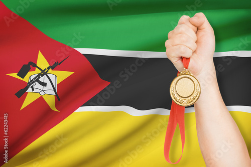 Medal in hand with flag on background - Republic of Mozambique